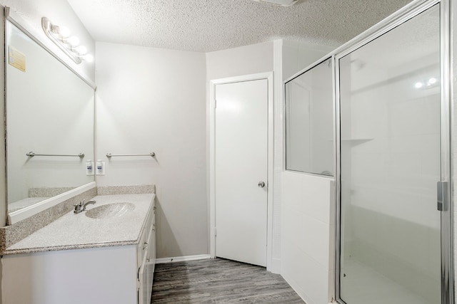 5606 Cypressgate Dr, Spring, TX 77373 - bathroom with vanity, wood finished floors, a stall shower, a textured ceiling, and baseboards
