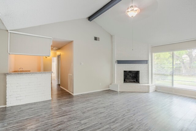 5606 Cypressgate Dr, Spring, TX 77373 - unfurnished living room with wood finished floors, beam ceiling, a ceiling fan, a fireplace, and baseboards