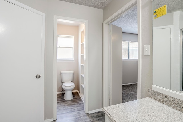 5606 Cypressgate Dr, Spring, TX 77373 - bathroom with toilet, wood finished floors, a textured ceiling, vanity, and baseboards