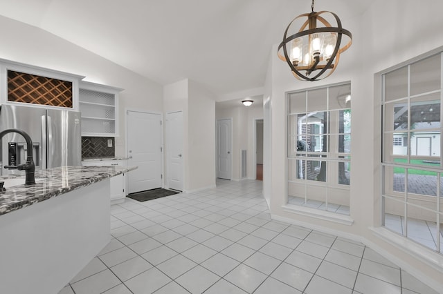 2457 Pebblebrook Cir, Conroe, TX 77384 - kitchen with stainless steel fridge, vaulted ceiling, a chandelier, white cabinets, and stone counters