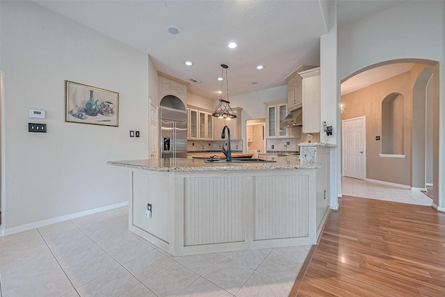 14202 Valley Bend Ct, Sugar Land, TX 77498 - kitchen with stainless steel built in refrigerator, a peninsula, light stone countertops, glass insert cabinets, and recessed lighting