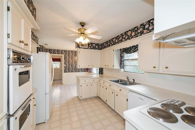 6211 Darby Way, Spring, TX 77389 - kitchen featuring wallpapered walls, white appliances, a sink, light flooring, and wall chimney range hood