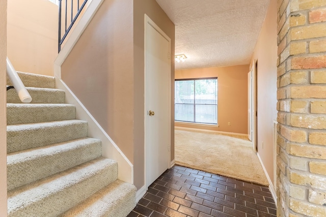 518 Lorie Ln, Pasadena, TX 77586 - stairway featuring a textured ceiling, brick flooring, carpet, and baseboards