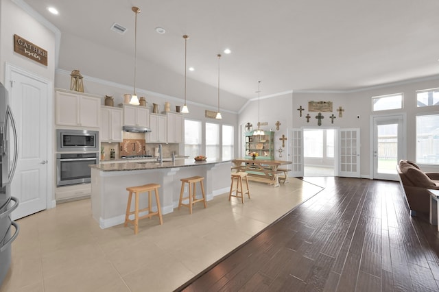 9103 Lacombe Ln, Tomball, TX 77375 - kitchen featuring appliances with stainless steel finishes, a kitchen breakfast bar, white cabinets, an island with sink, and stone counters