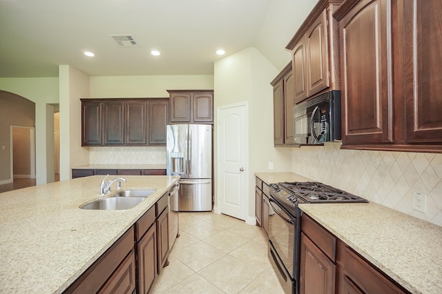 14110 Green Thicket Dr, Pearland, TX 77584 - kitchen featuring black appliances, a sink, arched walkways, tasteful backsplash, and light stone counters