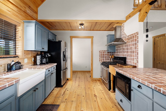 1012 Mourning Dove, Canyon Lake, TX 78133 - kitchen with tile countertops, stainless steel appliances, wall chimney range hood, tasteful backsplash, and wooden ceiling