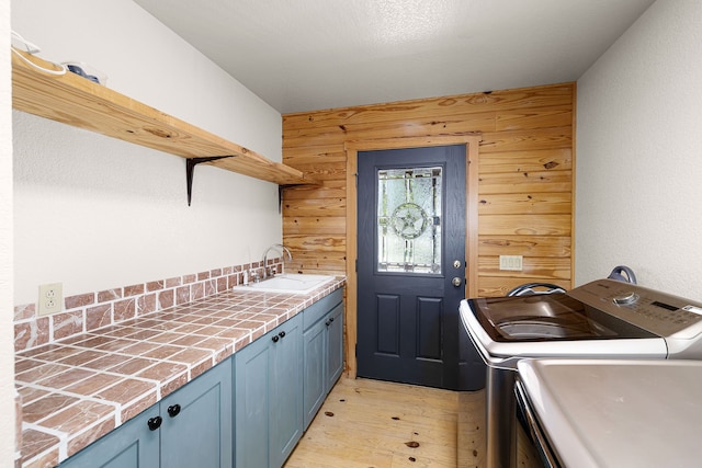 1012 Mourning Dove, Canyon Lake, TX 78133 - washroom featuring separate washer and dryer, cabinet space, light wood-style floors, and wooden walls