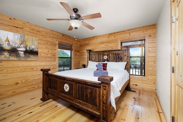 1012 Mourning Dove, Canyon Lake, TX 78133 - bedroom with light wood finished floors, wood walls, access to exterior, and ceiling fan