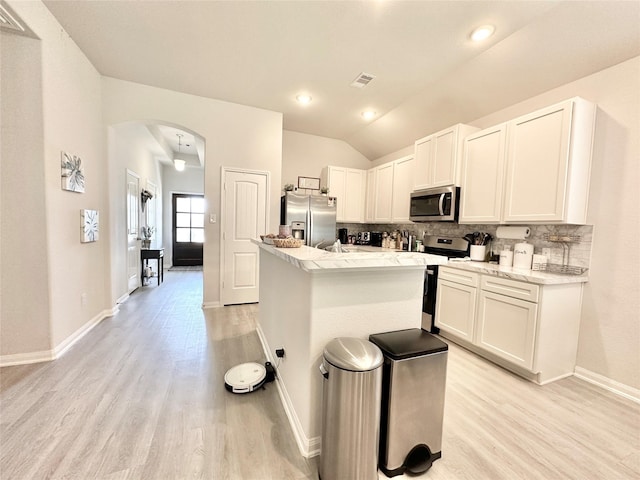 1410 Alice, Beaumont, TX 77705 - kitchen with stainless steel appliances, decorative backsplash, arched walkways, light wood-style flooring, and lofted ceiling