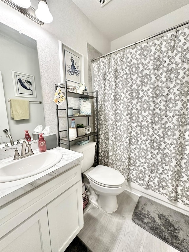 1410 Alice, Beaumont, TX 77705 - full bath with toilet, vanity, a shower with curtain, a textured wall, and wood finished floors