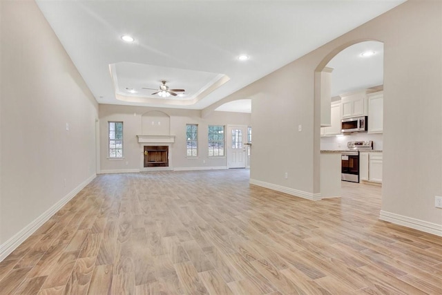 1805 Rollingwood Dr, Huntsville, TX 77340 - unfurnished living room featuring a ceiling fan, a raised ceiling, light wood-style flooring, baseboards, and recessed lighting