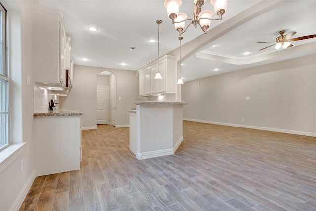 1805 Rollingwood Dr, Huntsville, TX 77340 - kitchen with arched walkways, white cabinets, light stone counters, open floor plan, and recessed lighting