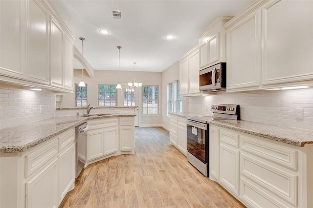 1805 Rollingwood Dr, Huntsville, TX 77340 - kitchen featuring stainless steel appliances, a sink, a chandelier, a peninsula, and backsplash