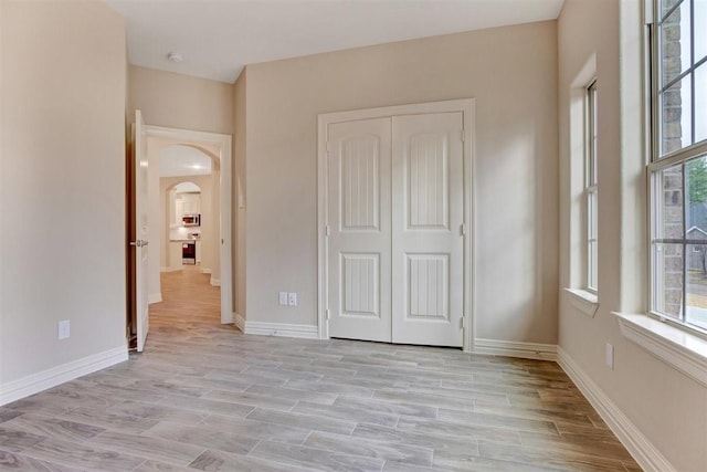1805 Rollingwood Dr, Huntsville, TX 77340 - unfurnished bedroom with multiple windows, arched walkways, a closet, and baseboards