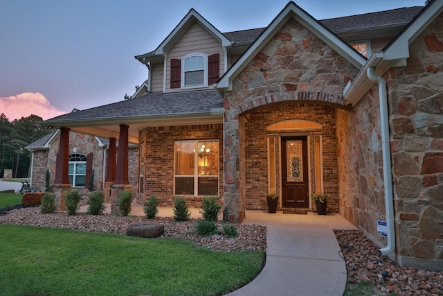 29122 Champions Dr, Magnolia, TX 77355 - doorway to property with stone siding, roof with shingles, a lawn, and a porch