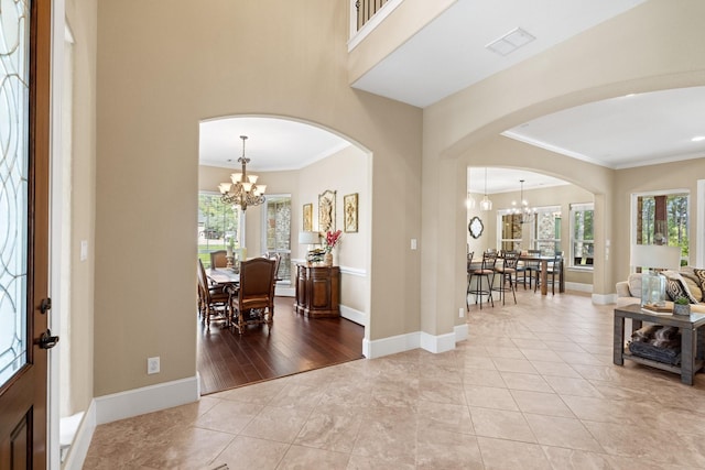 29122 Champions Dr, Magnolia, TX 77355 - foyer featuring arched walkways, a chandelier, crown molding, baseboards, and light tile patterned floors