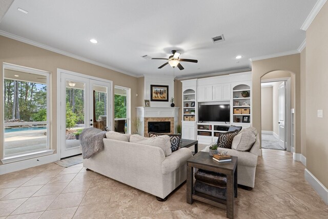 29122 Champions Dr, Magnolia, TX 77355 - living room featuring ornamental molding, ceiling fan, light tile patterned floors, a fireplace, and arched walkways