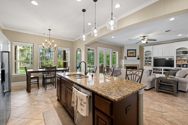29122 Champions Dr, Magnolia, TX 77355 - kitchen with stainless steel dishwasher, a sink, healthy amount of natural light, a fireplace, and crown molding