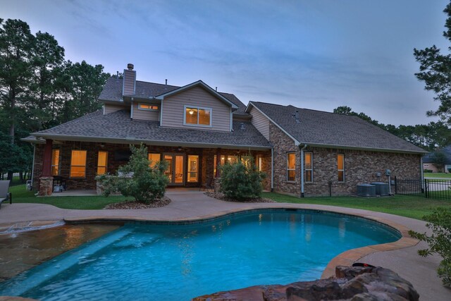 29122 Champions Dr, Magnolia, TX 77355 - back of house at dusk featuring a chimney, a patio area, and an outdoor pool