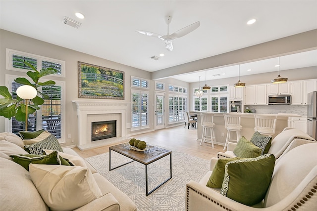 1405 Blueberry Ln, Friendswood, TX 77546 - living room featuring light wood finished floors, recessed lighting, a ceiling fan, and a warm lit fireplace