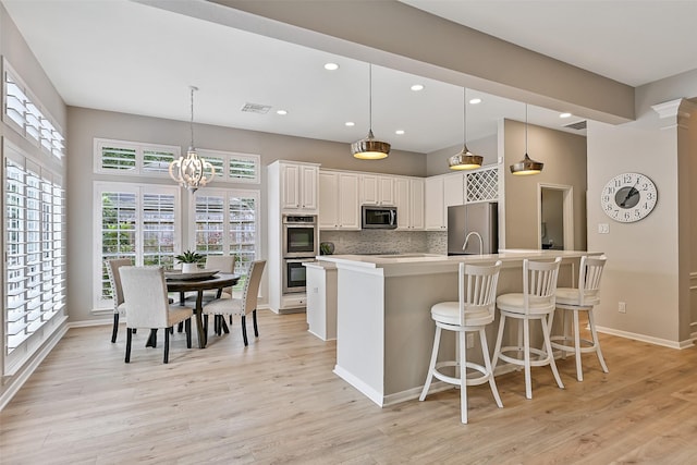 1405 Blueberry Ln, Friendswood, TX 77546 - kitchen with appliances with stainless steel finishes, light wood-style flooring, light countertops, a kitchen breakfast bar, and backsplash
