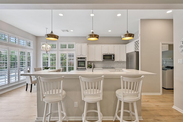 1405 Blueberry Ln, Friendswood, TX 77546 - kitchen with appliances with stainless steel finishes, light countertops, light wood finished floors, white cabinetry, and backsplash