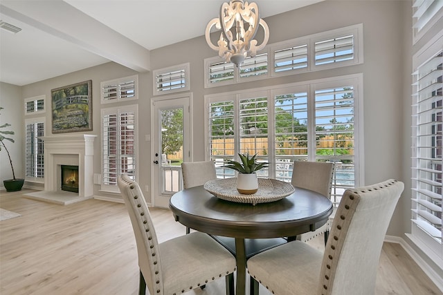 1405 Blueberry Ln, Friendswood, TX 77546 - dining room featuring a chandelier, light wood finished floors, a warm lit fireplace, and baseboards