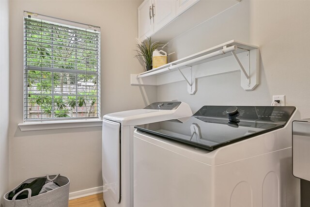 1405 Blueberry Ln, Friendswood, TX 77546 - laundry room featuring washer and clothes dryer, cabinet space, baseboards, and light wood-type flooring