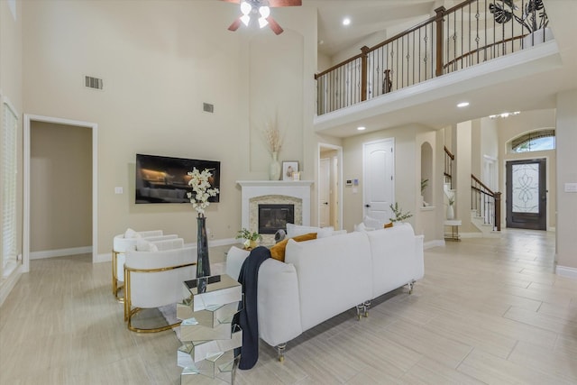 16815 Bornish Hill Ct, Humble, TX 77346 - living area featuring a towering ceiling, stairway, ceiling fan, a glass covered fireplace, and baseboards