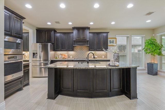 16815 Bornish Hill Ct, Humble, TX 77346 - kitchen with appliances with stainless steel finishes, a sink, tasteful backsplash, recessed lighting, and a kitchen island with sink