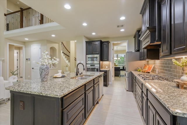 16815 Bornish Hill Ct, Humble, TX 77346 - kitchen featuring a sink, stainless steel appliances, tasteful backsplash, a large island with sink, and light stone countertops