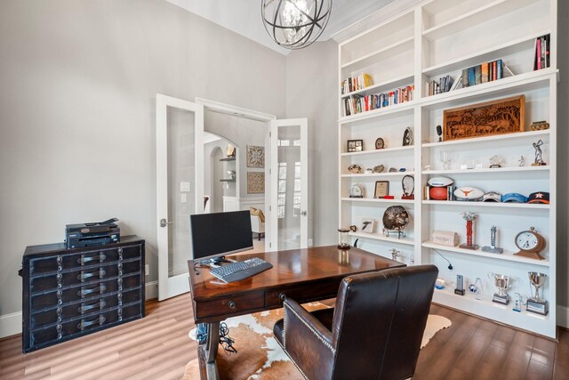 13 Honey Daffodil Pl, The Woodlands, TX 77380 - home office featuring wood finished floors, a chandelier, arched walkways, built in shelves, and french doors