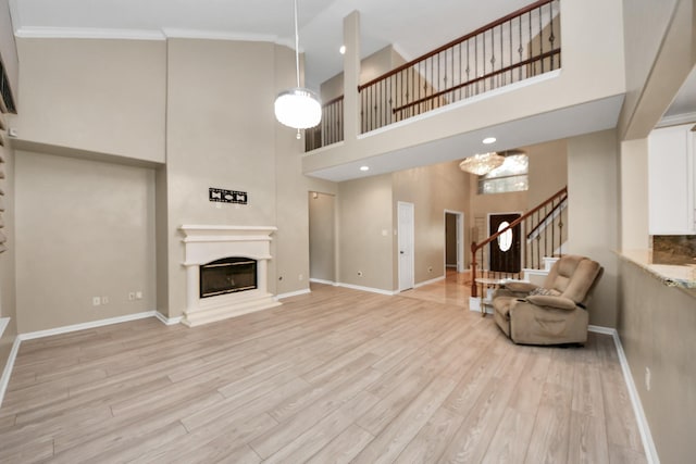 20902 Montana Bend Ln, Cypress, TX 77433 - living area with a high ceiling, baseboards, a glass covered fireplace, light wood-style floors, and ornamental molding