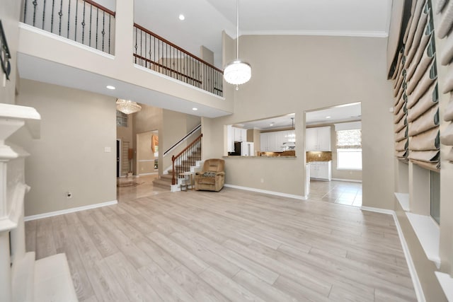 20902 Montana Bend Ln, Cypress, TX 77433 - unfurnished living room featuring stairs, crown molding, a towering ceiling, light wood finished floors, and baseboards