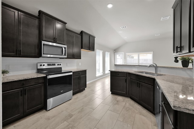 115 Clear Water St W, Montgomery, TX 77356 - kitchen with appliances with stainless steel finishes, a sink, lofted ceiling, light stone counters, and dark cabinets