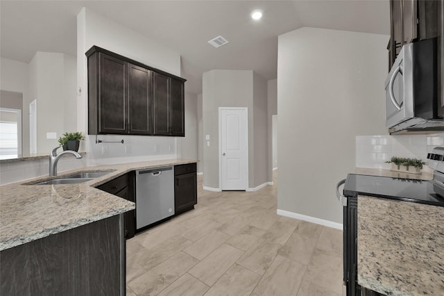 115 Clear Water St W, Montgomery, TX 77356 - kitchen with appliances with stainless steel finishes, a sink, light stone counters, decorative backsplash, and lofted ceiling