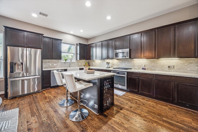 1115 E 27th St, Houston, TX 77009 - kitchen featuring stainless steel appliances, dark brown cabinets, a kitchen island, dark wood finished floors, and recessed lighting