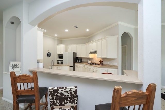 301 Redwood St, Prairie View, TX 77445 - kitchen featuring arched walkways, appliances with stainless steel finishes, ornamental molding, a peninsula, and a kitchen breakfast bar