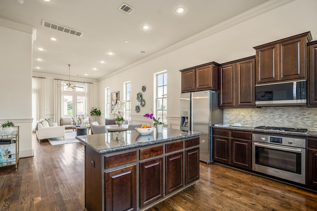 1217 E 28th St, Houston, TX 77009 - kitchen featuring appliances with stainless steel finishes, ornamental molding, healthy amount of natural light, dark stone countertops, and a center island