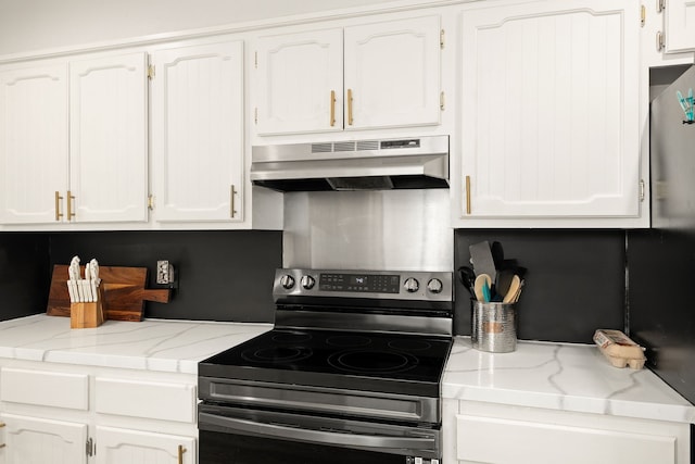 402 Teakwood Dr, Victoria, TX 77901 - kitchen with under cabinet range hood, electric stove, white cabinetry, and light stone counters