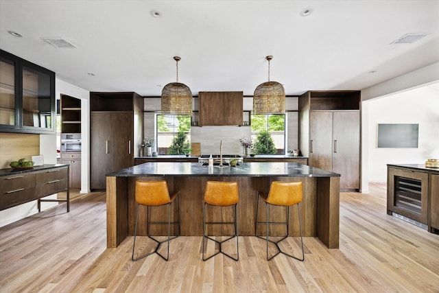 703 E 9th St, Houston, TX 77007 - kitchen featuring a kitchen island, light wood-style floors, a breakfast bar area, and pendant lighting