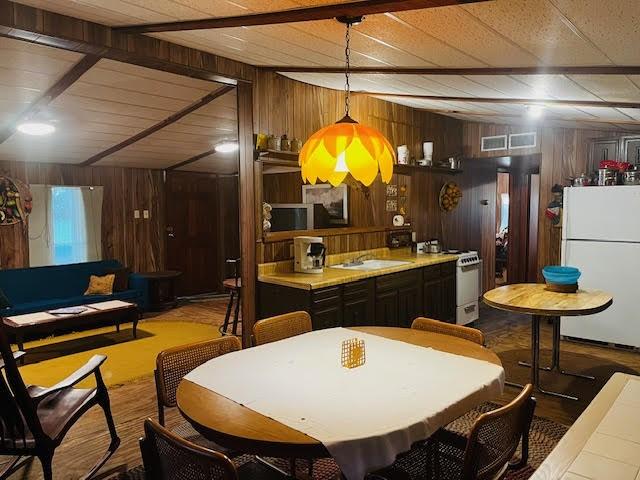 11200 Leisure Rd, Brenham, TX 77833 - kitchen with white appliances, wood finished floors, wood walls, decorative light fixtures, and a sink