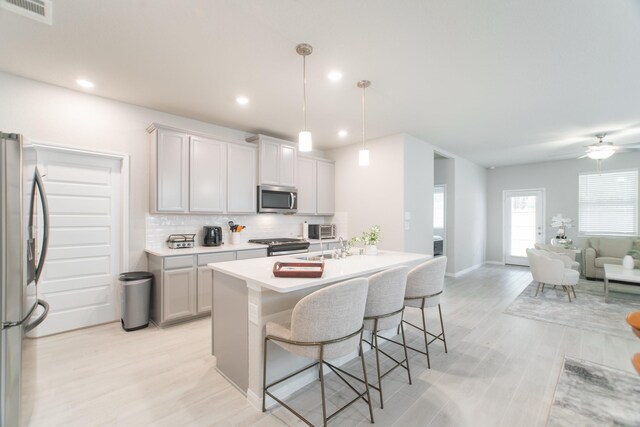 17542 Rosette Grass Dr, Conroe, TX 77385 - kitchen featuring appliances with stainless steel finishes, open floor plan, decorative backsplash, a breakfast bar area, and light countertops