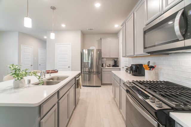 17542 Rosette Grass Dr, Conroe, TX 77385 - kitchen featuring stainless steel appliances, gray cabinetry, a sink, tasteful backsplash, and light countertops