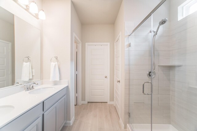 17542 Rosette Grass Dr, Conroe, TX 77385 - bathroom featuring a shower stall, double vanity, wood finished floors, and baseboards