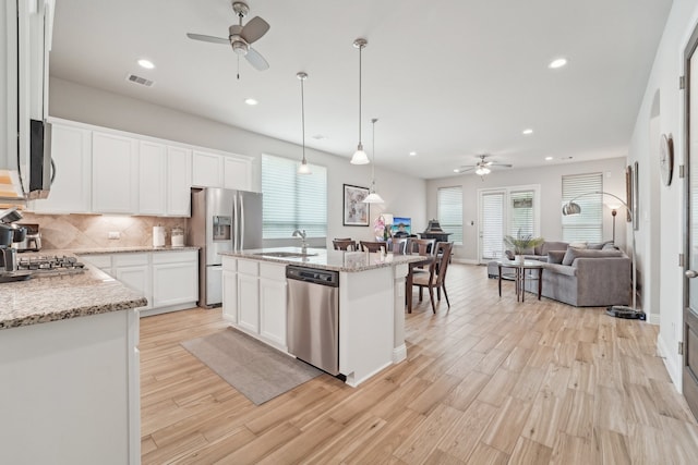 10029 Red Beadtree Pl, Conroe, TX 77385 - kitchen featuring a ceiling fan, stainless steel appliances, open floor plan, a sink, and decorative backsplash