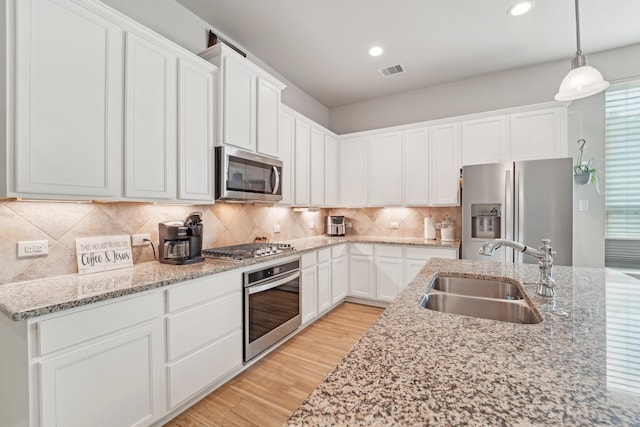 10029 Red Beadtree Pl, Conroe, TX 77385 - kitchen with appliances with stainless steel finishes, a sink, light wood-style floors, white cabinetry, and recessed lighting