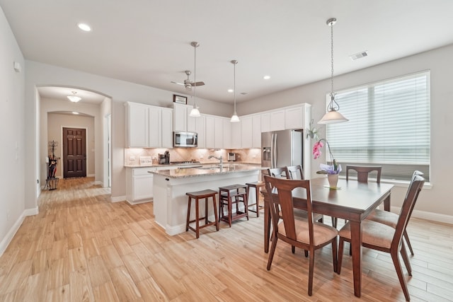 10029 Red Beadtree Pl, Conroe, TX 77385 - dining space featuring arched walkways, light wood-style floors, ceiling fan, recessed lighting, and baseboards