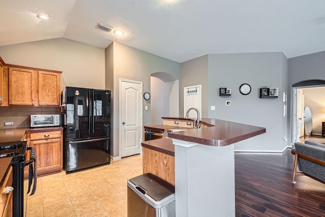2604 Hewn Rock Way, Pearland, TX 77584 - kitchen featuring black appliances, arched walkways, dark countertops, a sink, and a center island with sink