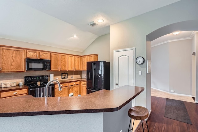 2604 Hewn Rock Way, Pearland, TX 77584 - kitchen featuring black appliances, dark countertops, arched walkways, vaulted ceiling, and a breakfast bar